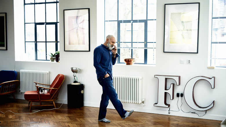 A senior man walking in his home while talking on the phone.