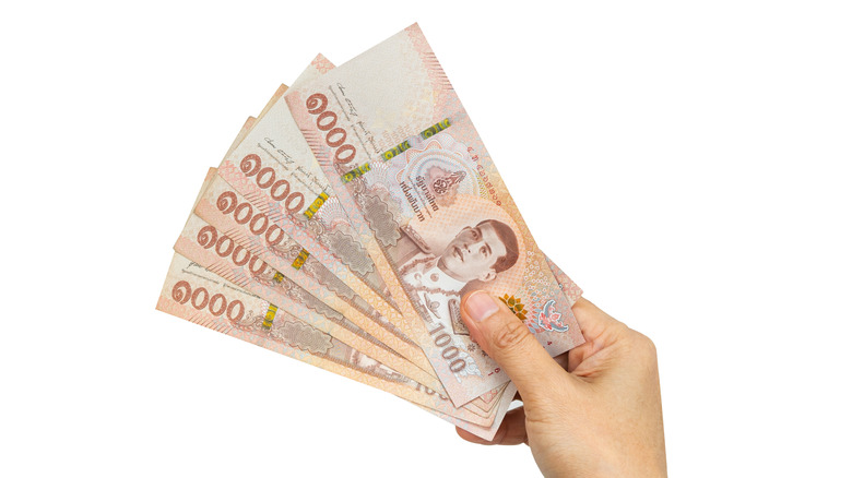 Hand holds five1,000 baht bank notes