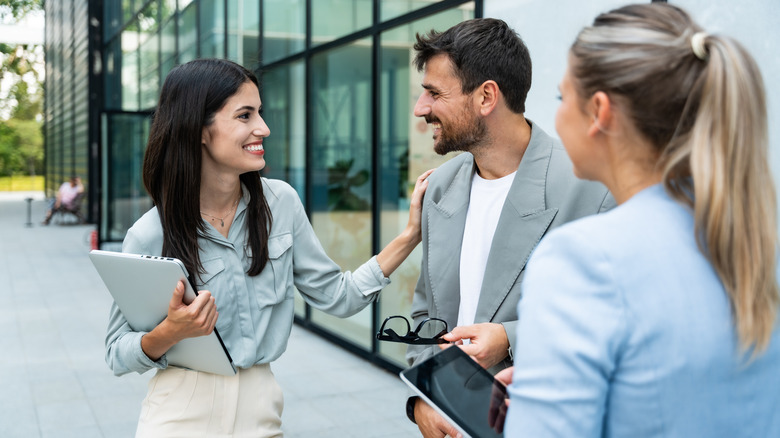 Group of young successful business people standing out of office building in formal wear