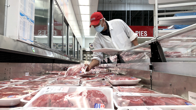 A Costco butcher stocking a meat cooler