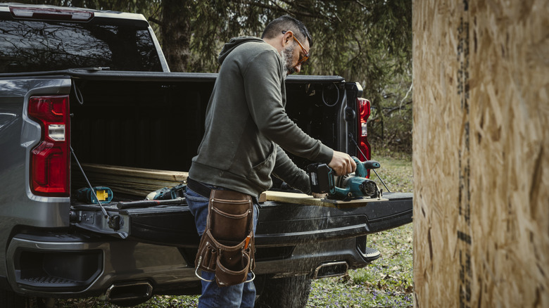 Man working in the bed of his open truck in the woods