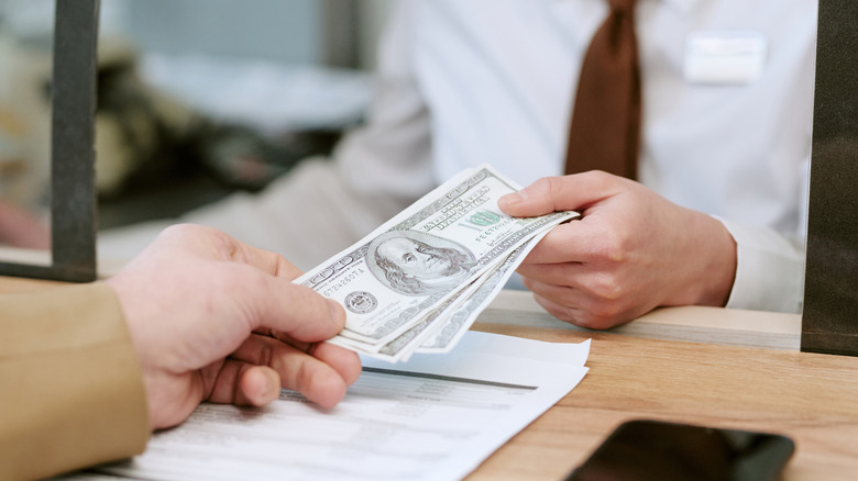 A bank teller handing cash to a client