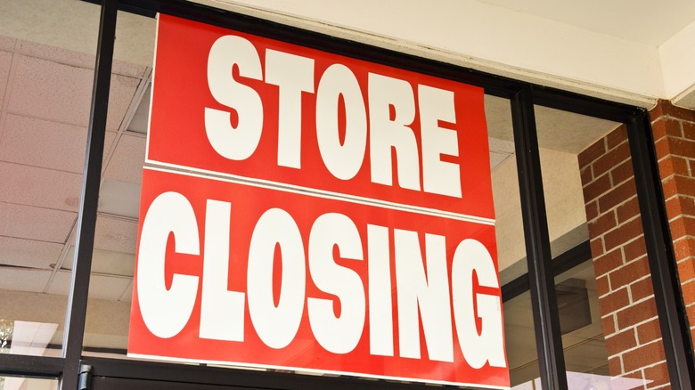 A large store closing sign in a retail store window.