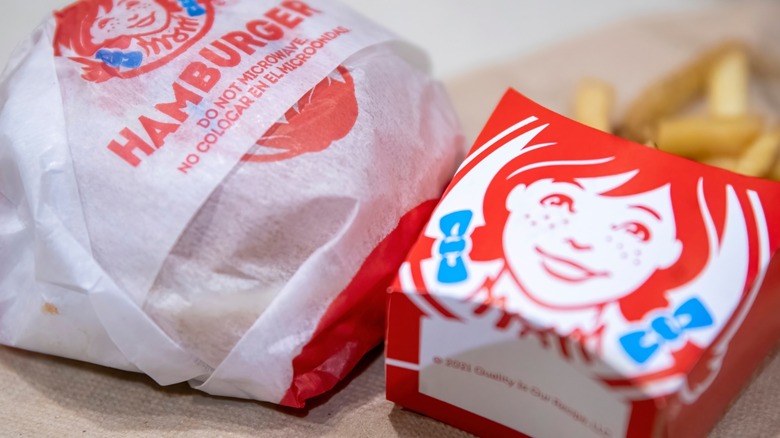 A burger and a side of fries from Wendy's sitting on a table.