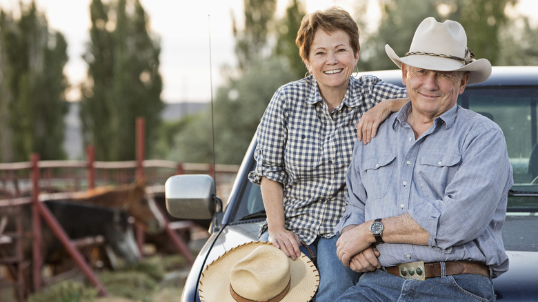 Older ranchers sitting on the hood of truck