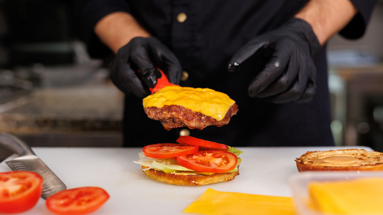A line cook assembling a cheeseburger