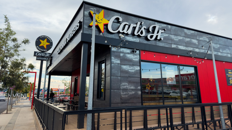 The exterior of a Carl's Jr. location on a street corner on a cloudy day