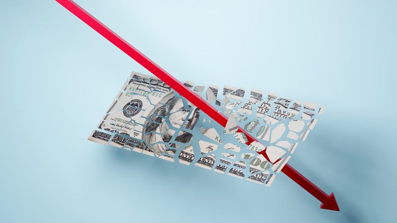 A one hundred dollar bill being destroyed by a downward arrow