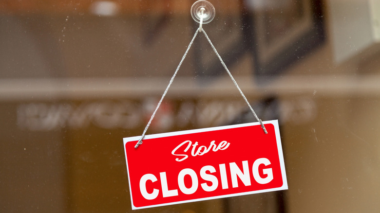 A red store closing sign hanging in a window