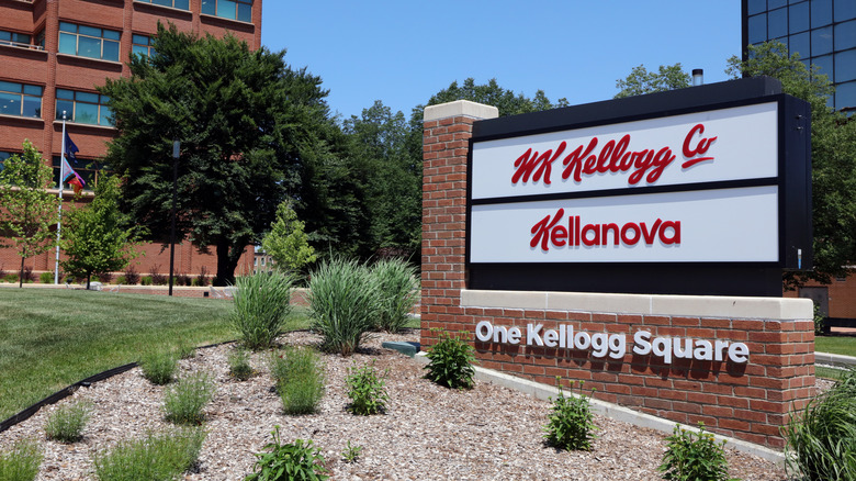 A sign for the offices of WK Kellogg Co. and Kellanova with office buildings and tress behind it