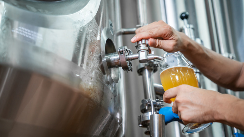 A beer being poured from a steel tank inside a brewery