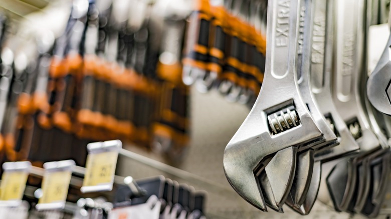Adjustable wrenches hanging on display beside rows of screwdrivers in a hardware store