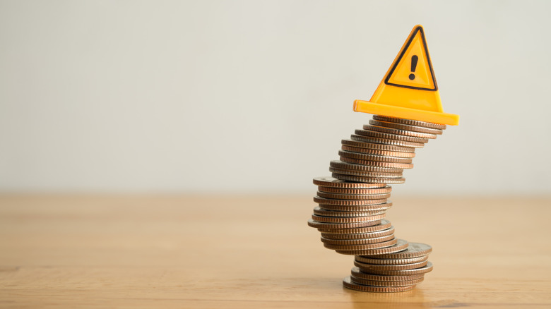 coins falling over with hazard cone on top of stack
