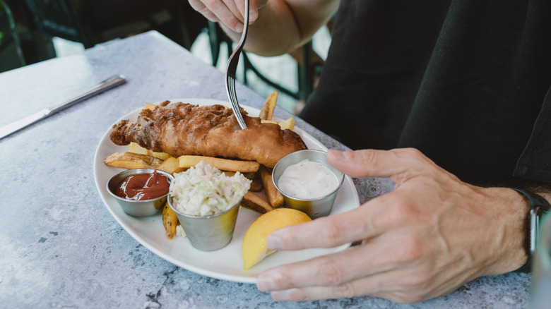 Person eating fish & chips in restaurant