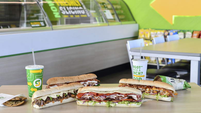 Subway sandwiches, drinks, and chips on a table in restaurant