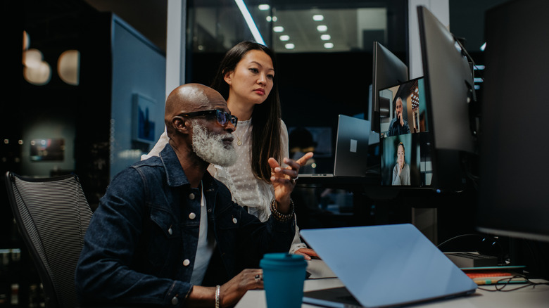 A older male and a young female employee work late in a modern office space.