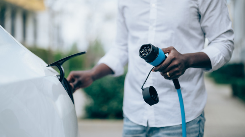 A man plugging in is electric vehicle to charge