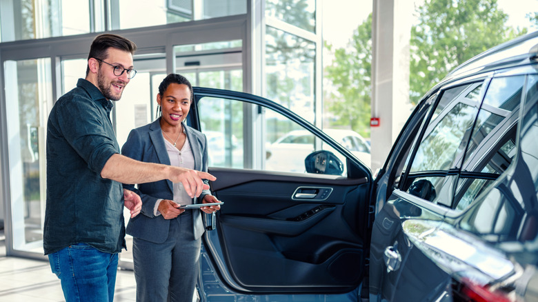 A young man and woman looking at a car in a dealership