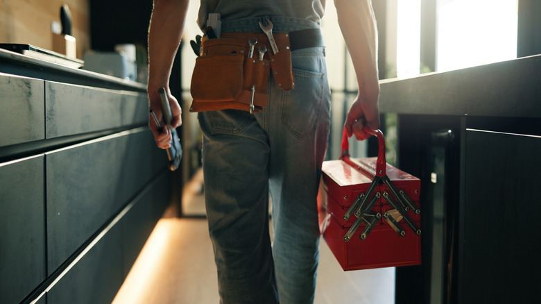 Main with a toolbox and belt in a kitchen