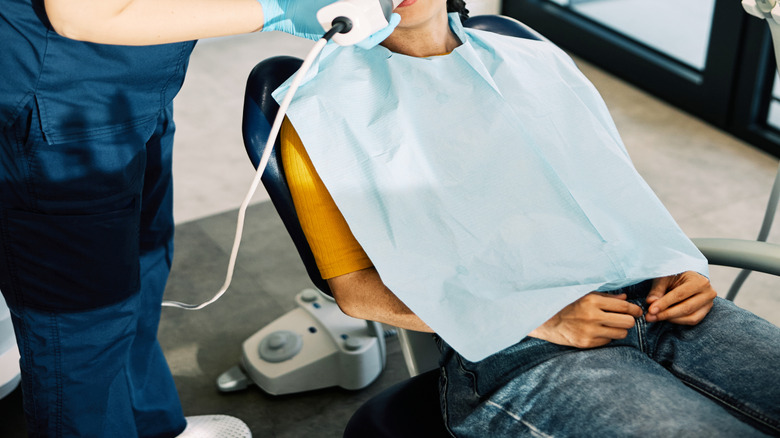 white female dentist exams teeth of Asian female patient