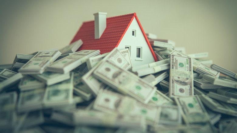 a house figurine covered by a pile of money