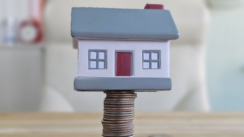 Model house standing on stack of coins, showing property value