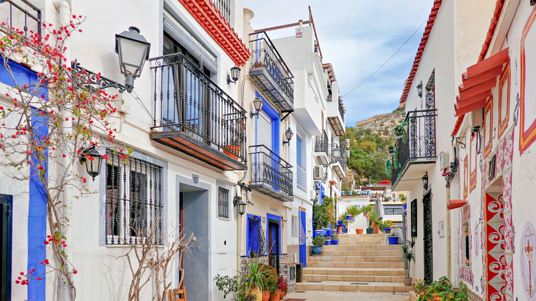 Narrow street in Alicante with white houses and colorful trim
