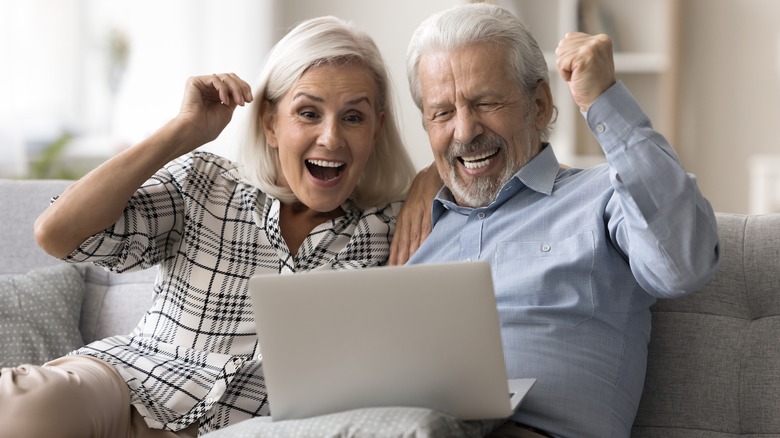 An celebratory mature couple looking at their laptop screen.