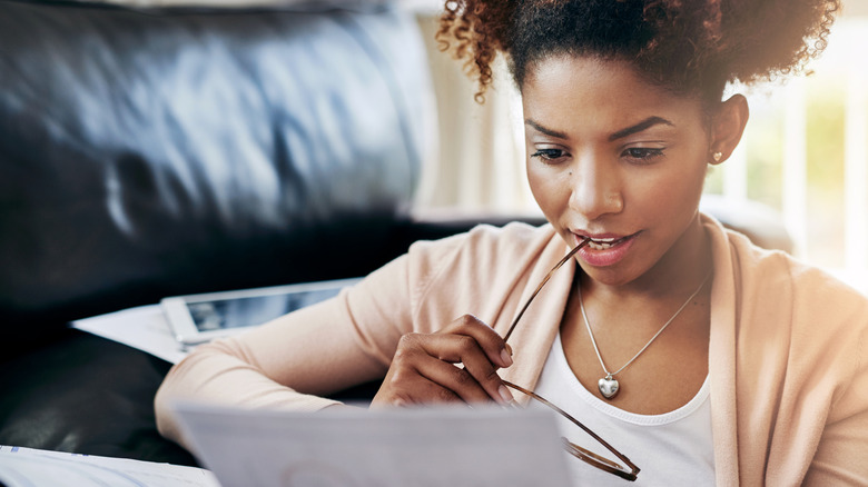 young woman looking at financial documents with a slight smile