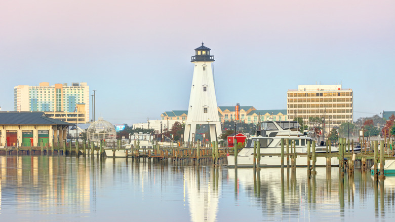 As senior women looking wistful at the water while sitting barefoot on a pier.