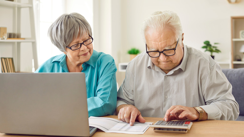 Retired senior couple performing calculations at a table