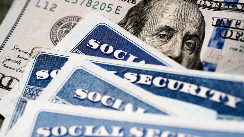 Social Security cards on top a United States $100 dollar bill