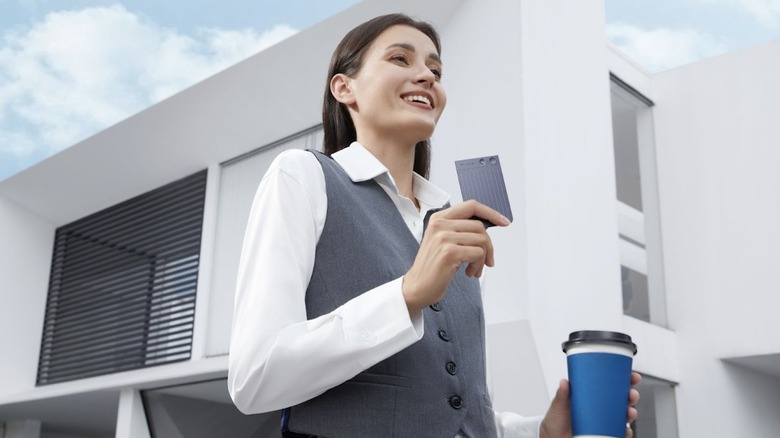 woman holding plaud.ai device and cup of coffee