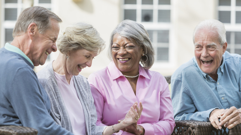 A seated group of seniors laughing in a retirement community.