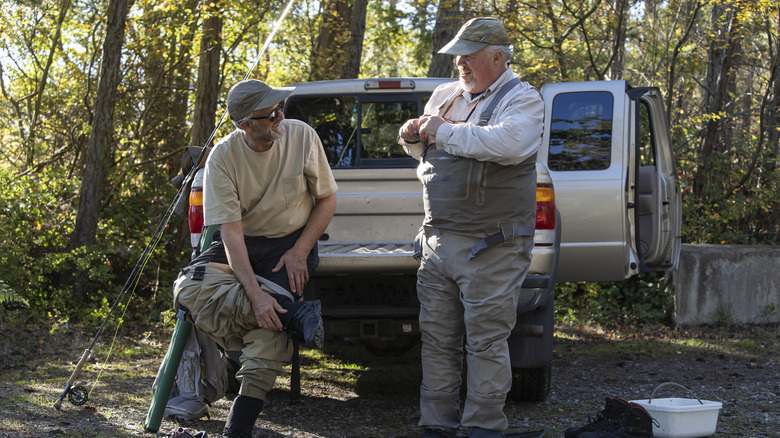 Two fishermen friends sitting on back of pick up truck