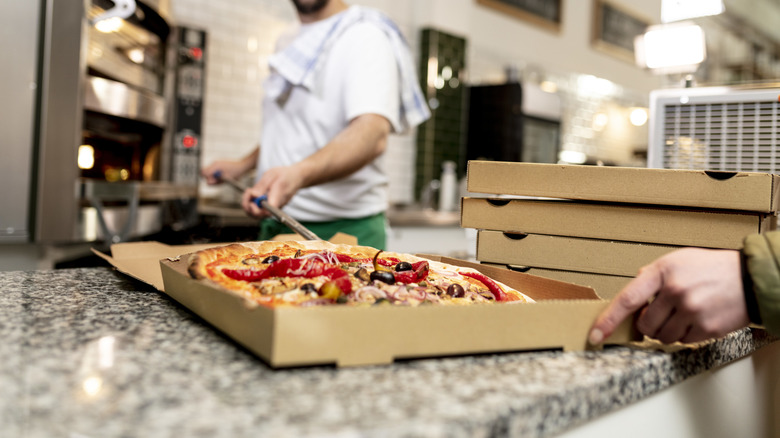 Pizza chef putting pizza in a box