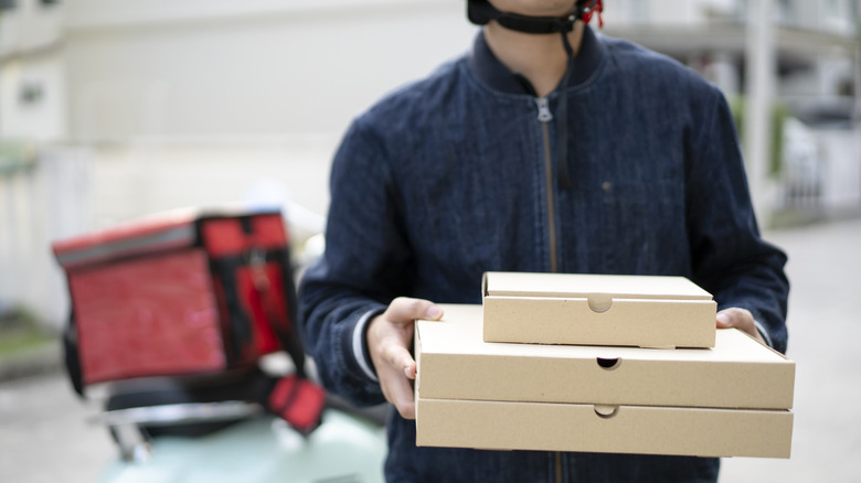 Pizza delivery person holding pizza boxes