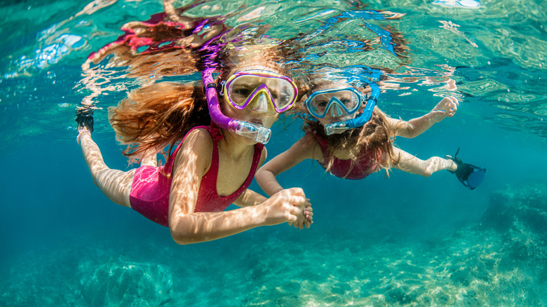 Two girls in pink swimsuits who are snorkeling