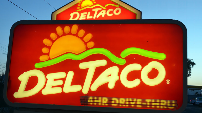 A glowing Del Taco drive-thru sign during blue twilight.