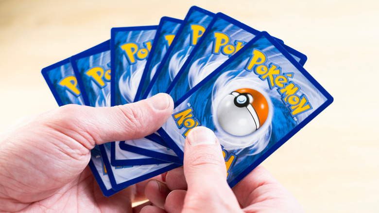 Hands holding a deck of Pokemon cards