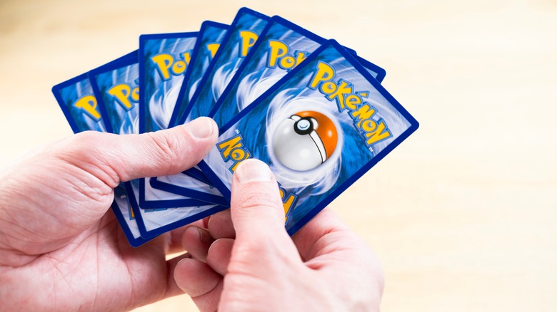 Hands holding a deck of Pokemon cards
