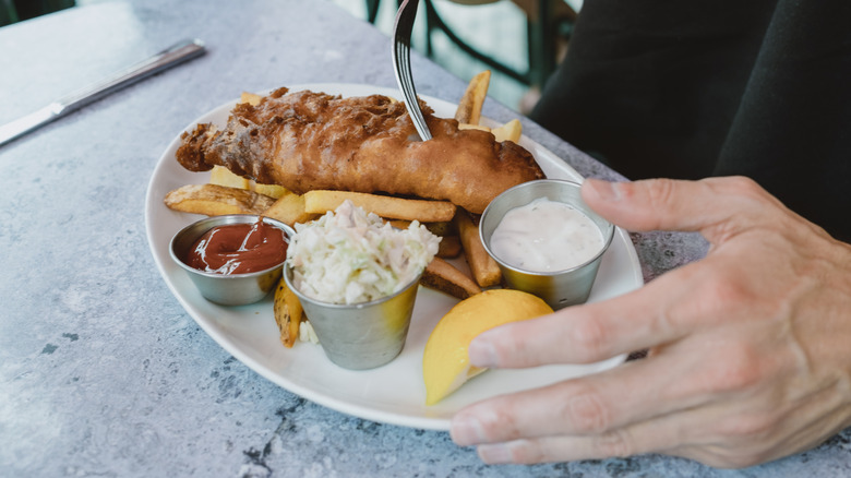 Person eating fish & chips in restaurant