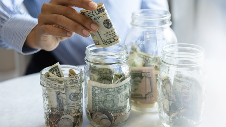 man in dress shirt placing cash in mason jars