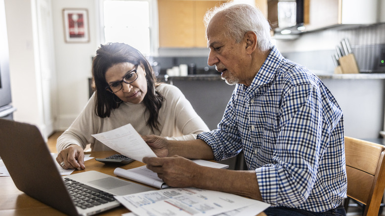 Senior couple paying bills at kitchen table