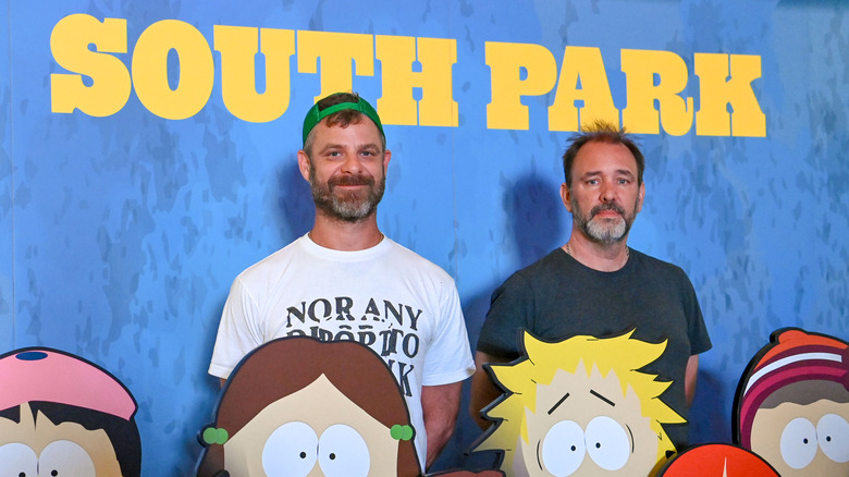 Trey Parker and Matt Stone standing in from of a South Park promotion