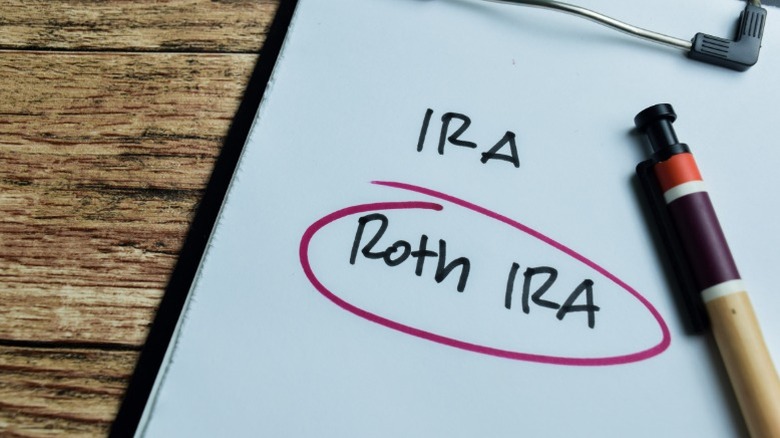 A clipboard with different IRA options written on a piece of paper with Roth IRA circled in marker.