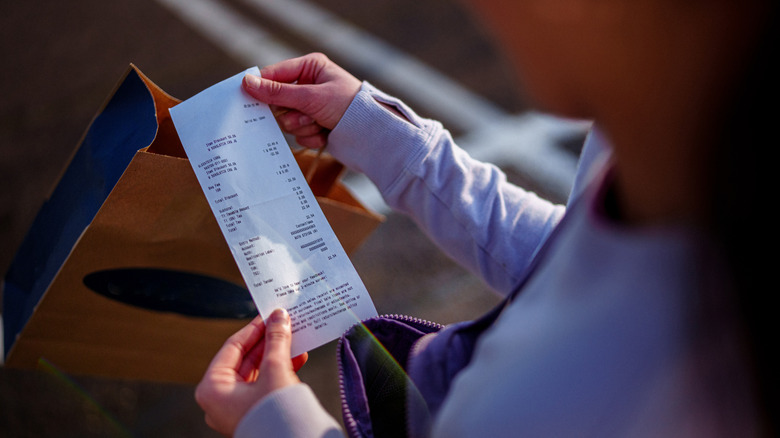 A person looking at a receipt in their hands.
