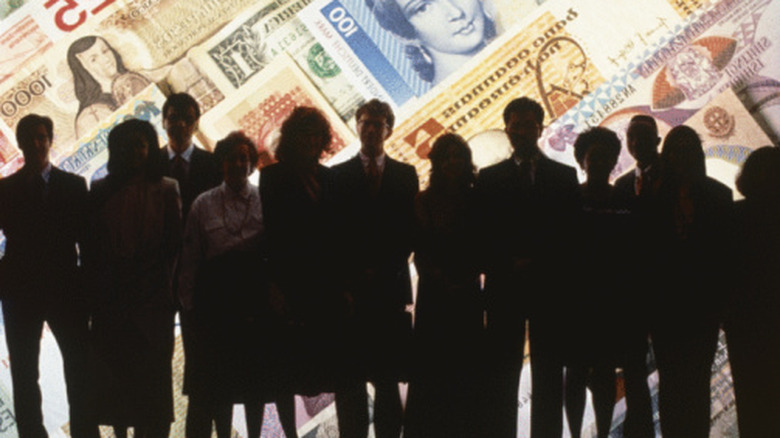 people in shadows in front of money