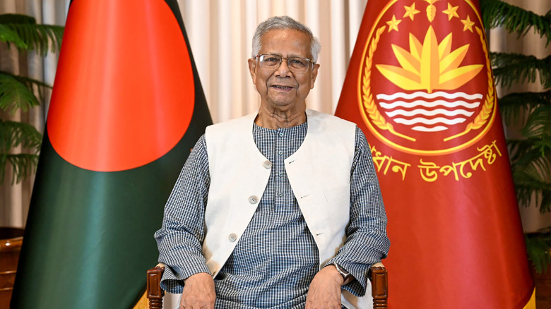 Muhammad Yunus sitting near flags