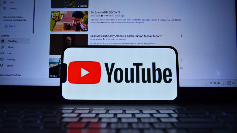 YouTube logo on phone in front of the page on computer